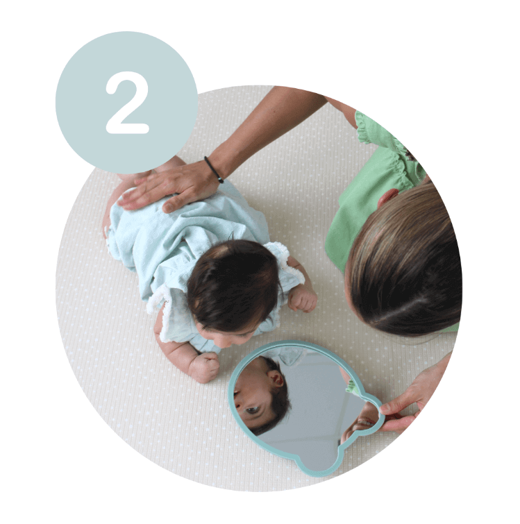 Small baby practicing tummy time with mirror