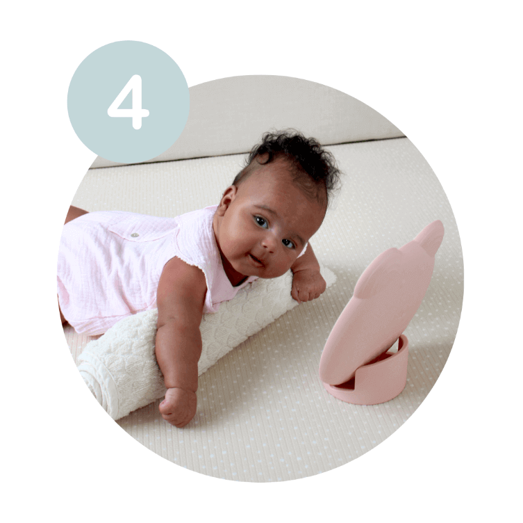 Baby using a towel to help with learning to lay on stomach